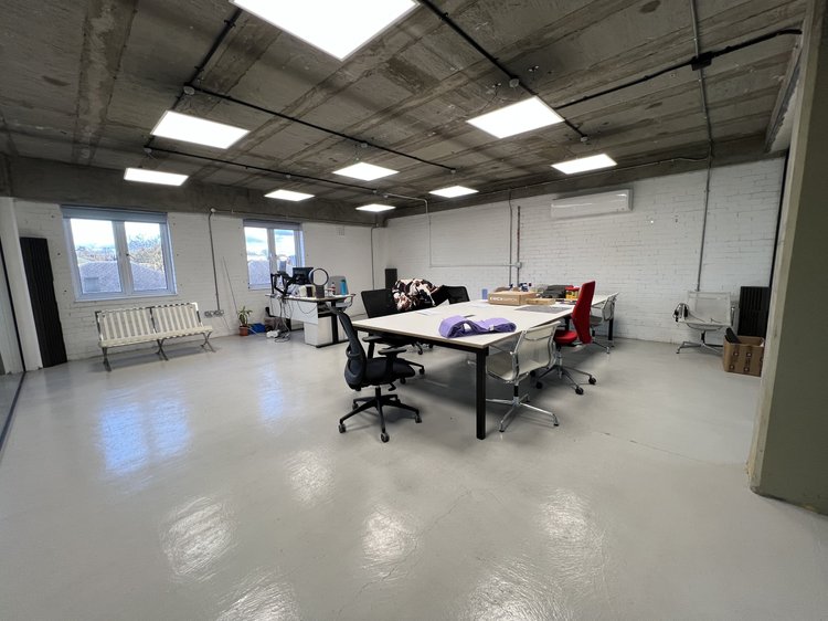 Open workspace with tables, office chairs and large windows.