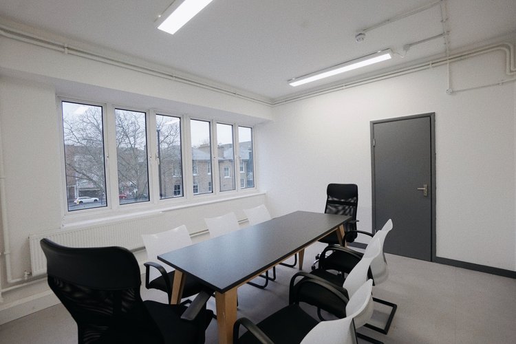 Meeting room with a long dark table, office chairs and large windows.