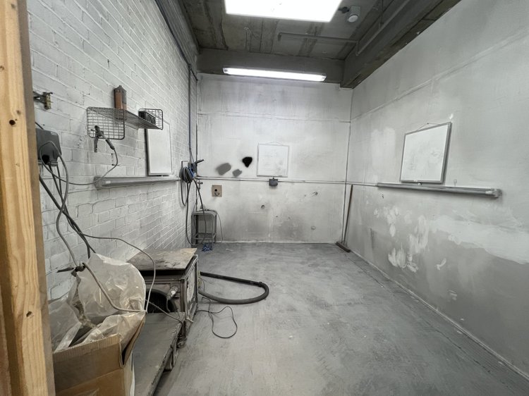 Industrial workroom with white brick walls, exposed services and work surfaces.