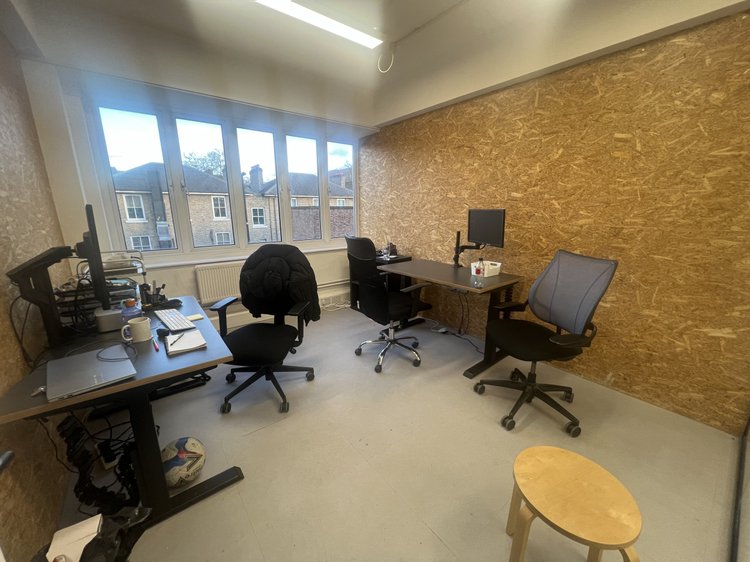 Private office with desks, chairs, a wooden wall and large windows.