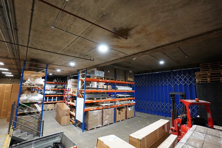 Storage area with racking, boxes, a blue loading door and handling equipment.
