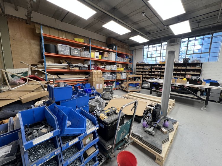 Workshop benches with tools, materials and blue storage bins.