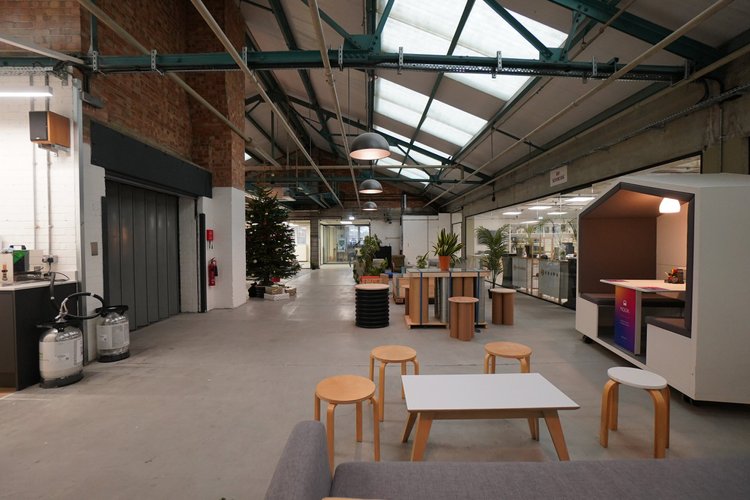 Shared lounge and kitchen area with stools, plants and an exposed roof structure.