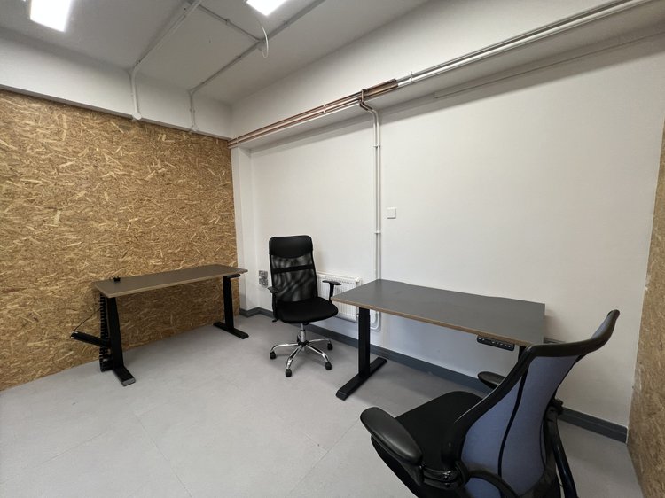 Private office with two desks, office chairs and a wooden accent wall.
