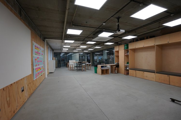 Open industrial workspace with wooden wall panels, tables and a whiteboard.