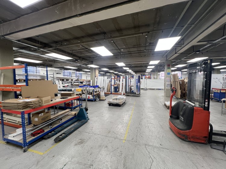 Large workshop and storage area with worktables, stock racks and a red pallet truck.