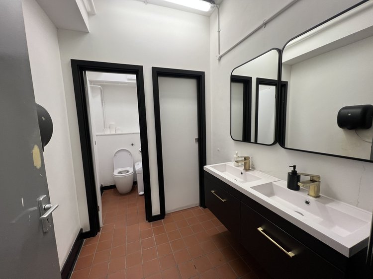Washroom with two basins, mirrors and an adjoining toilet cubicle.