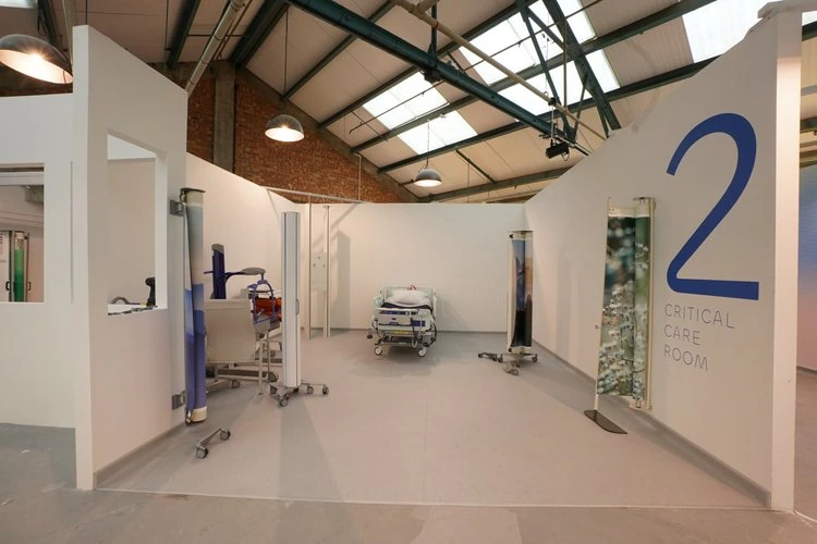 Clinical room with a hospital bed, medical equipment and privacy screens.