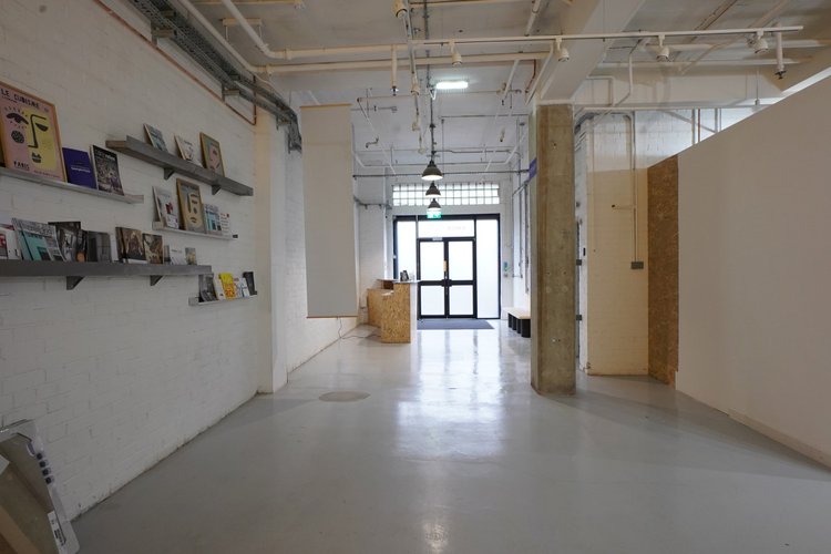 Entrance corridor with wall shelves, white brick walls and exposed services.
