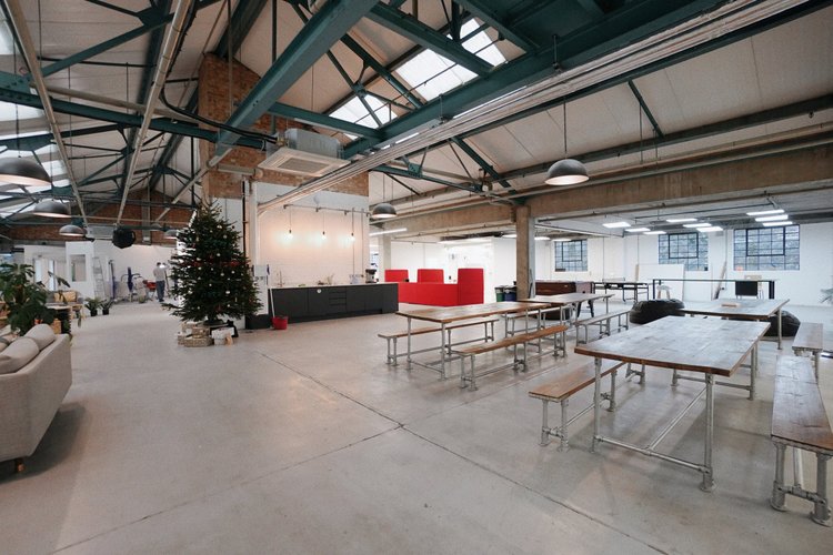 Large shared space with communal tables beneath exposed roof beams.
