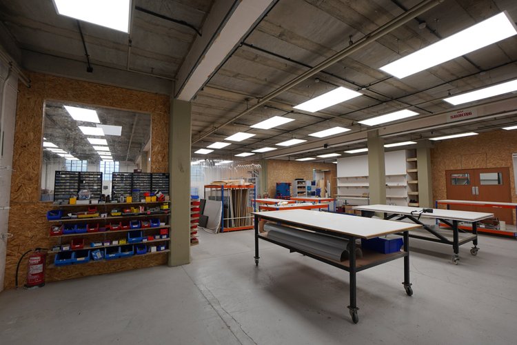 An empty workshop or classroom with tables, shelves, and storage bins.