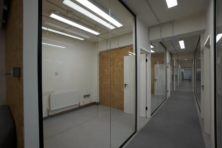 Glass-fronted offices opening onto a carpeted corridor.