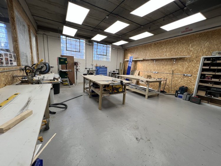 Woodworking workshop with benches, machinery and wall-mounted tool storage.