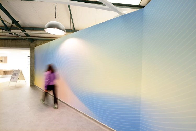 Person walking beside the curved blue corridor wall.