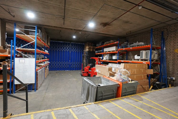 Warehouse storage area with racks, boxes and a blue loading door.