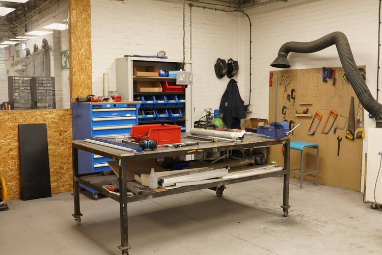 Wood workshop with blue tool drawers and tools arranged on a pegboard.