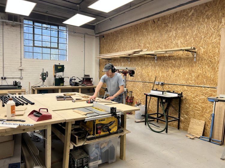 A maker working at a bench in the wood workshop.